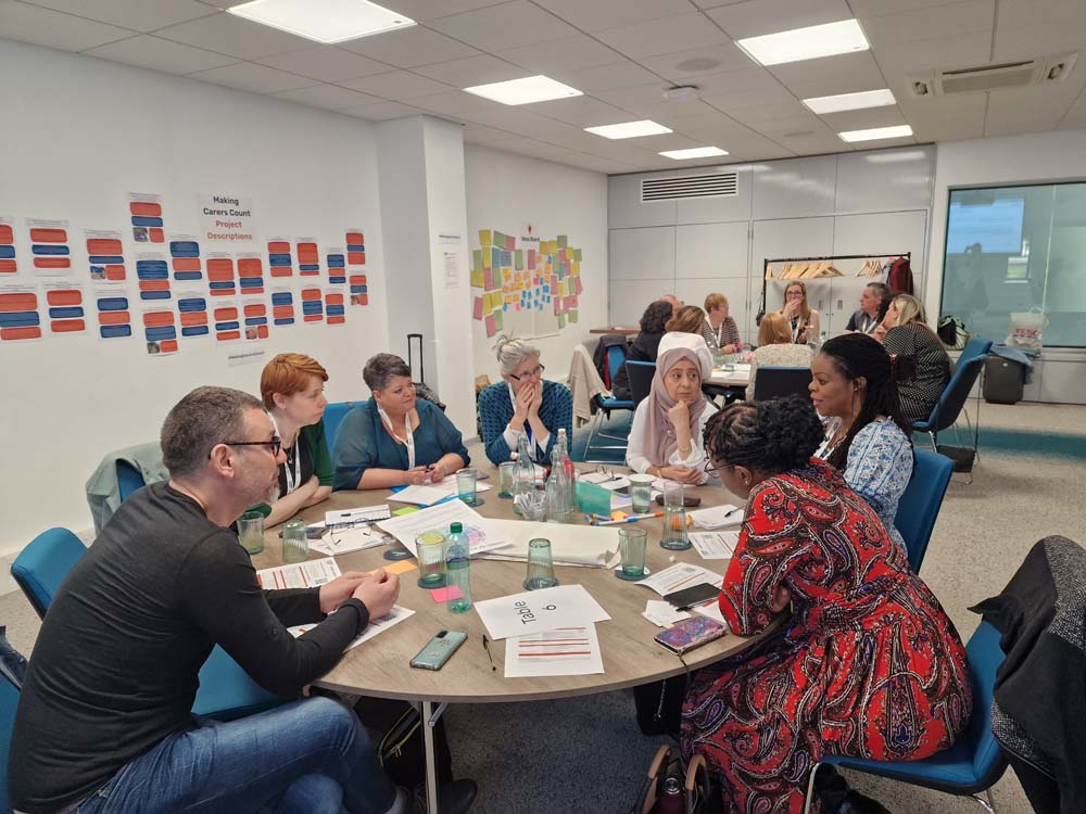 Group of carers having meeting around circular table.